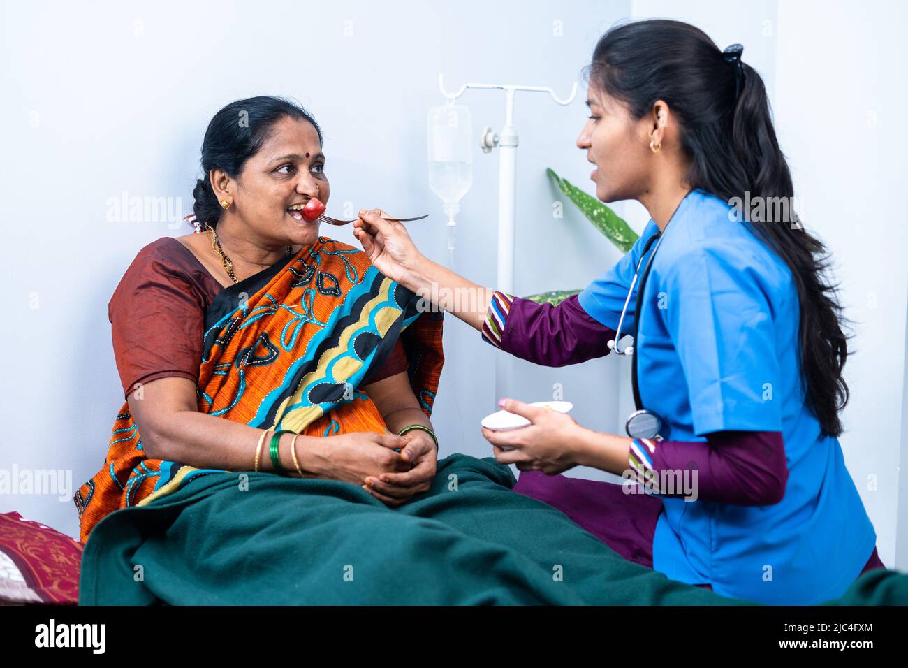 Nurse feeding sick woman to eat while on bed at nursing home - concept of support, medicare and caretaker Stock Photo
