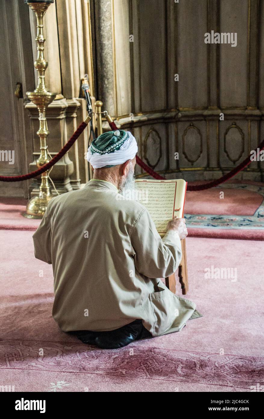 Old man reading Quran in a mosque on display Stock Photo