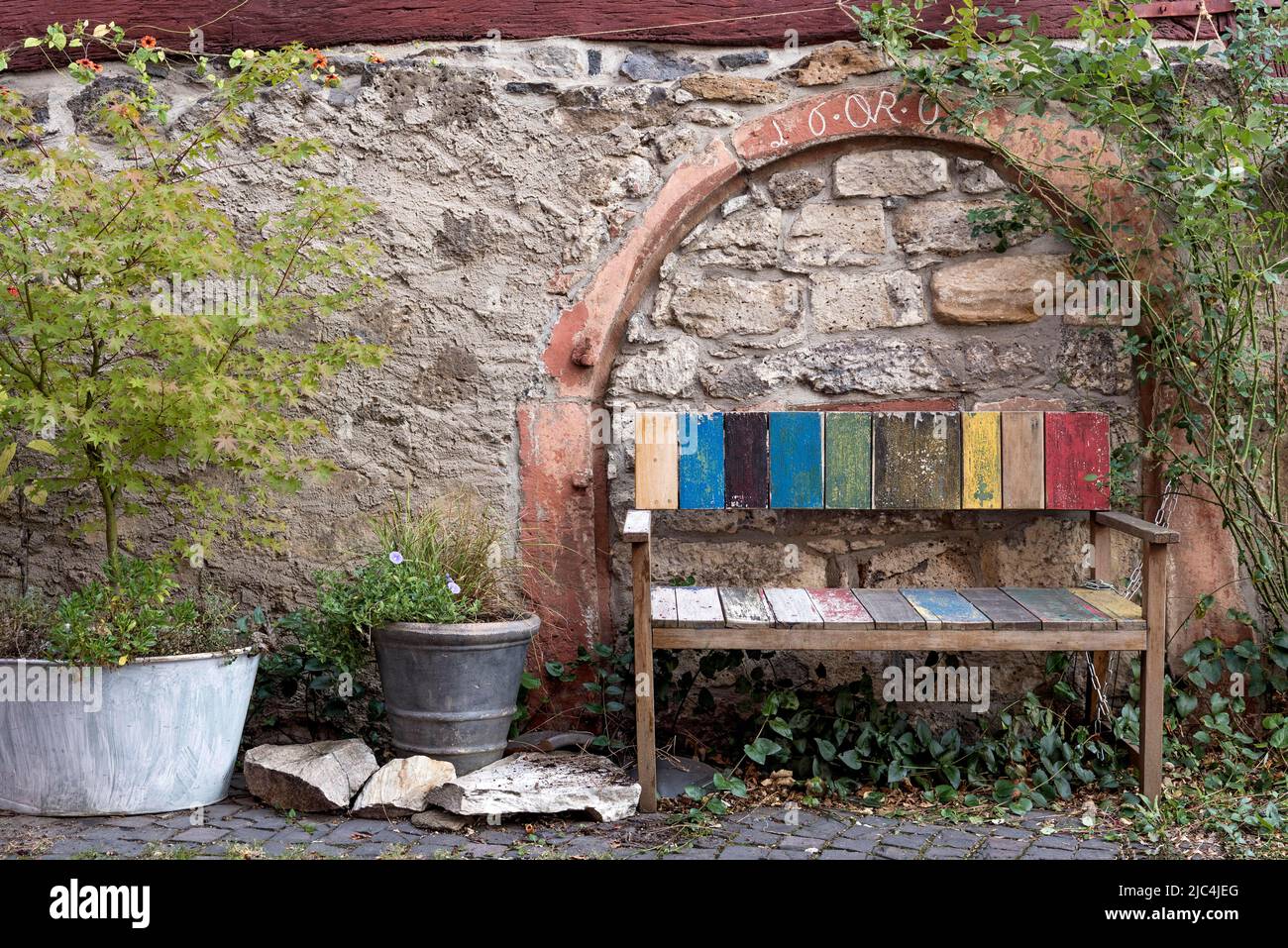 Germany Bench Old colourfully painted faded wooden bench and planter on house wall ...