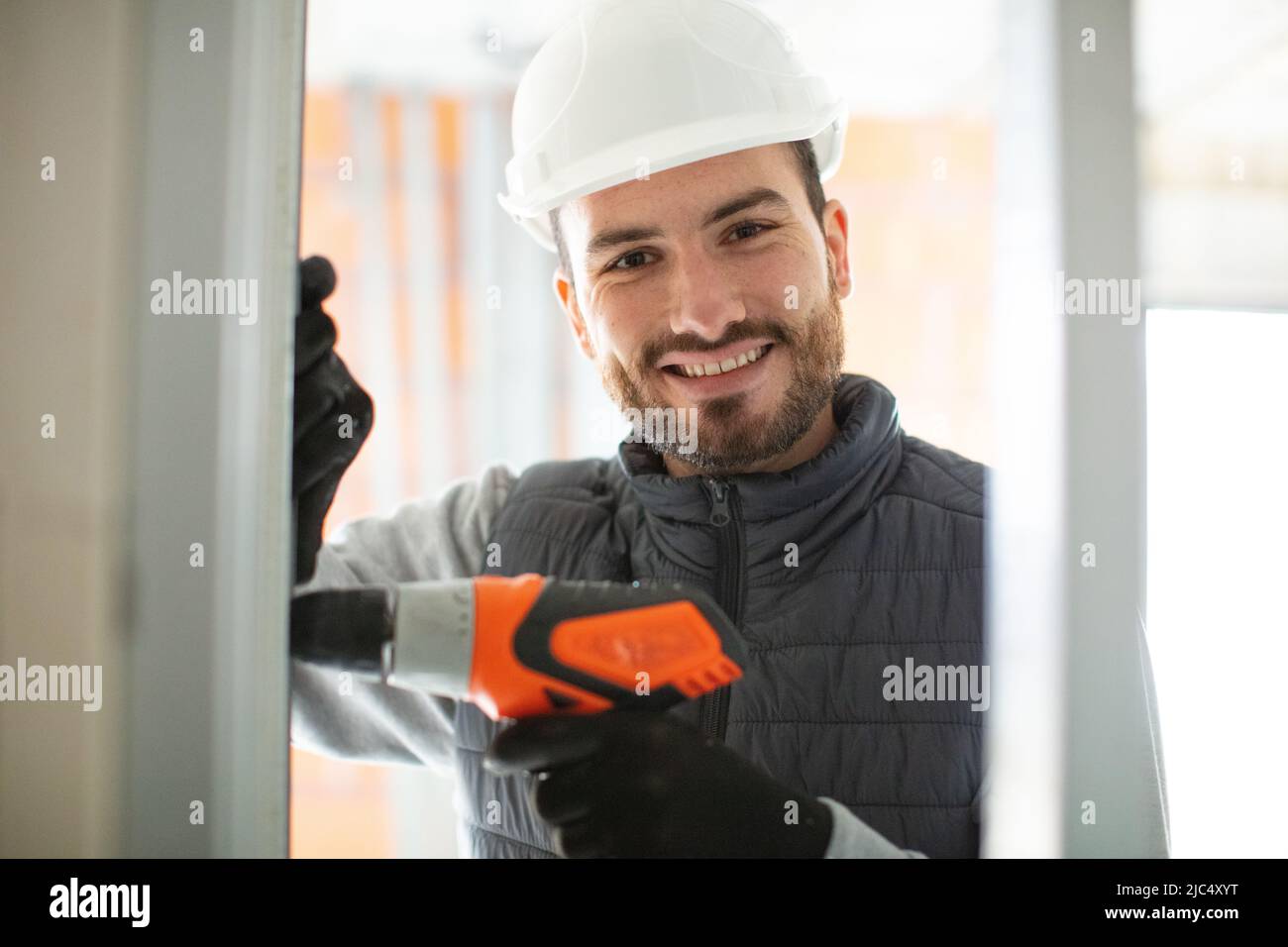 construction worker using drill to install window Stock Photo