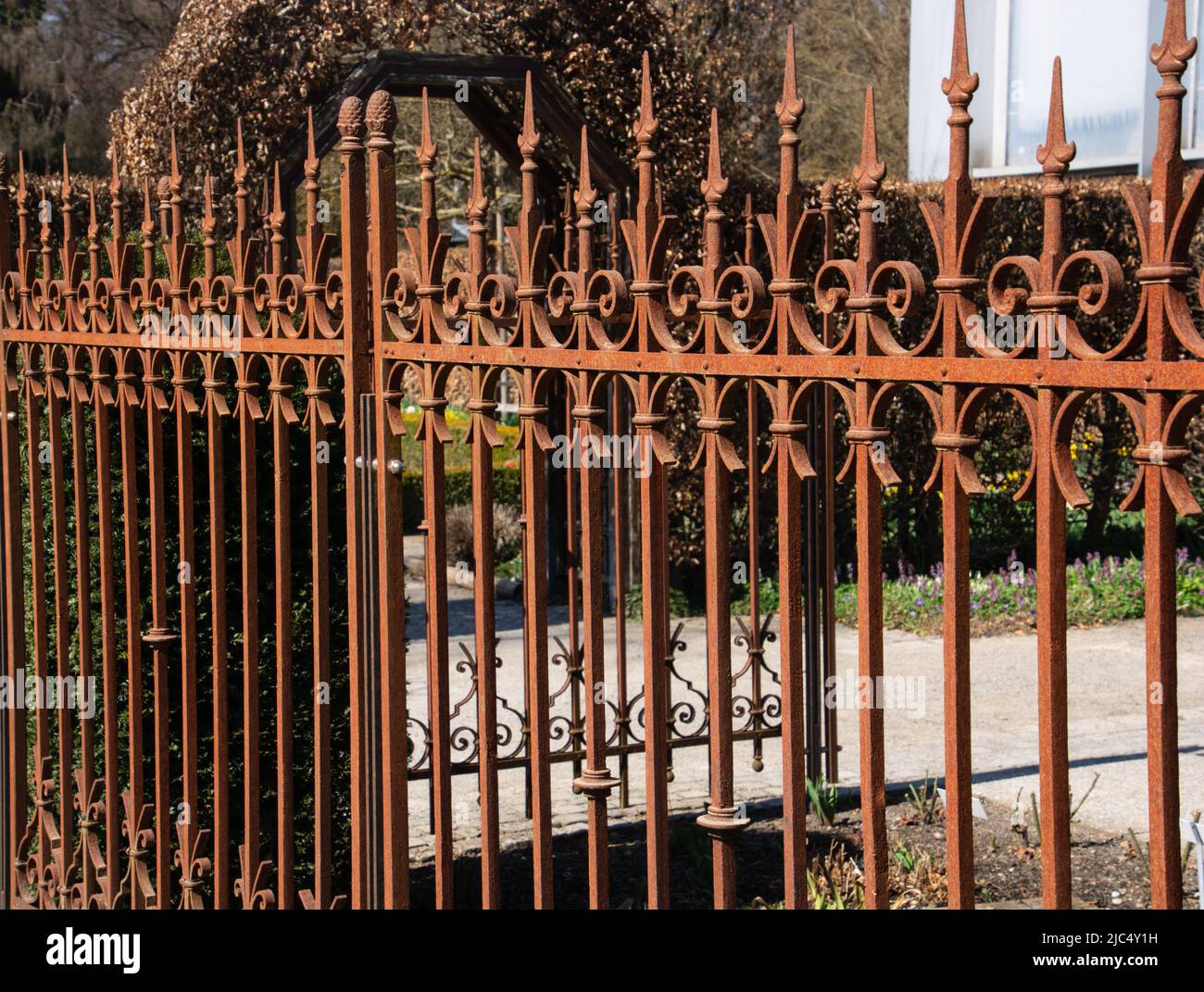 very decorative garden fence made of rusted wrought iron with a very nice entrance Stock Photo