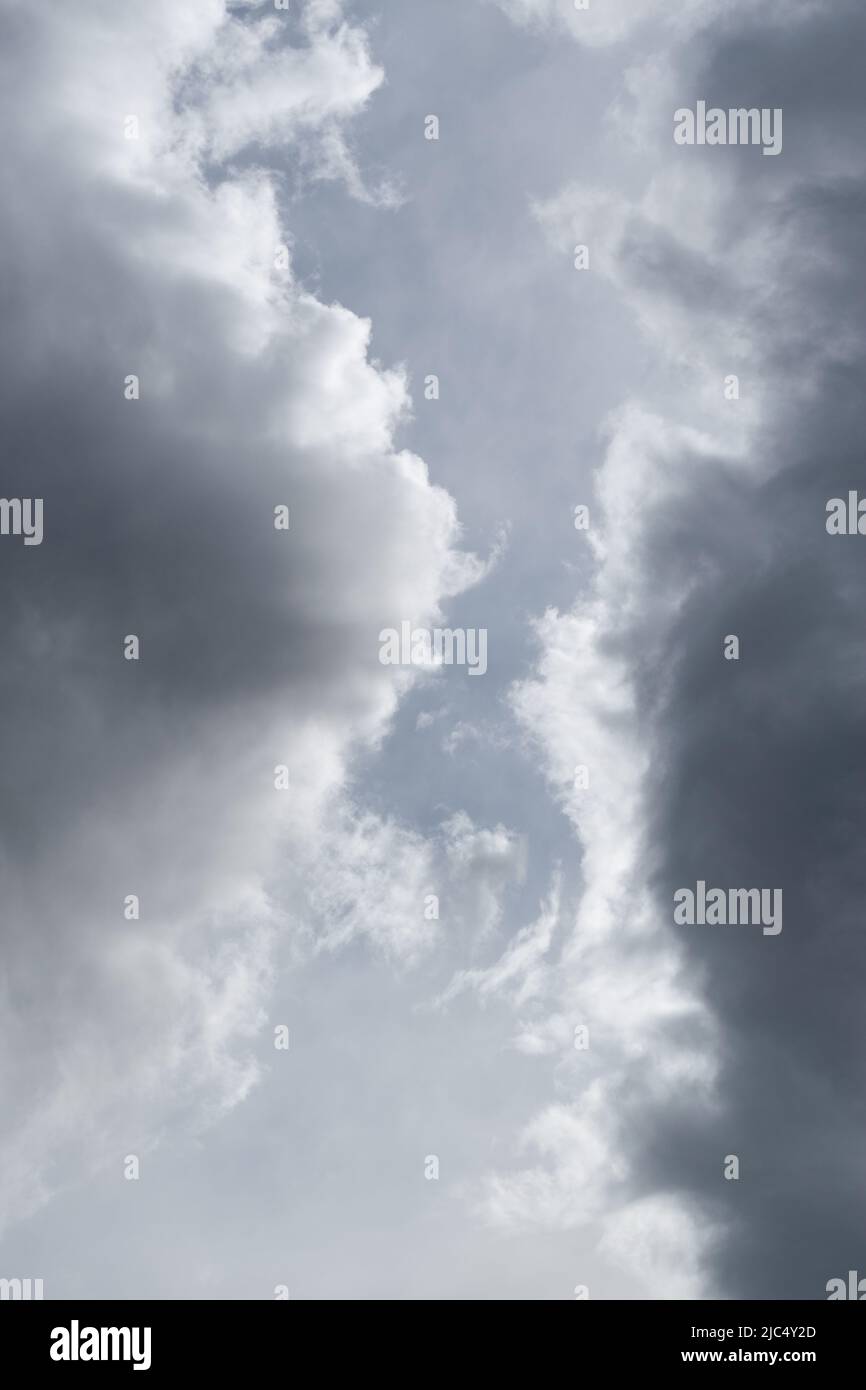 Two grey clouds passing each other with gap in middle, bright edge and dark center of cloud Stock Photo