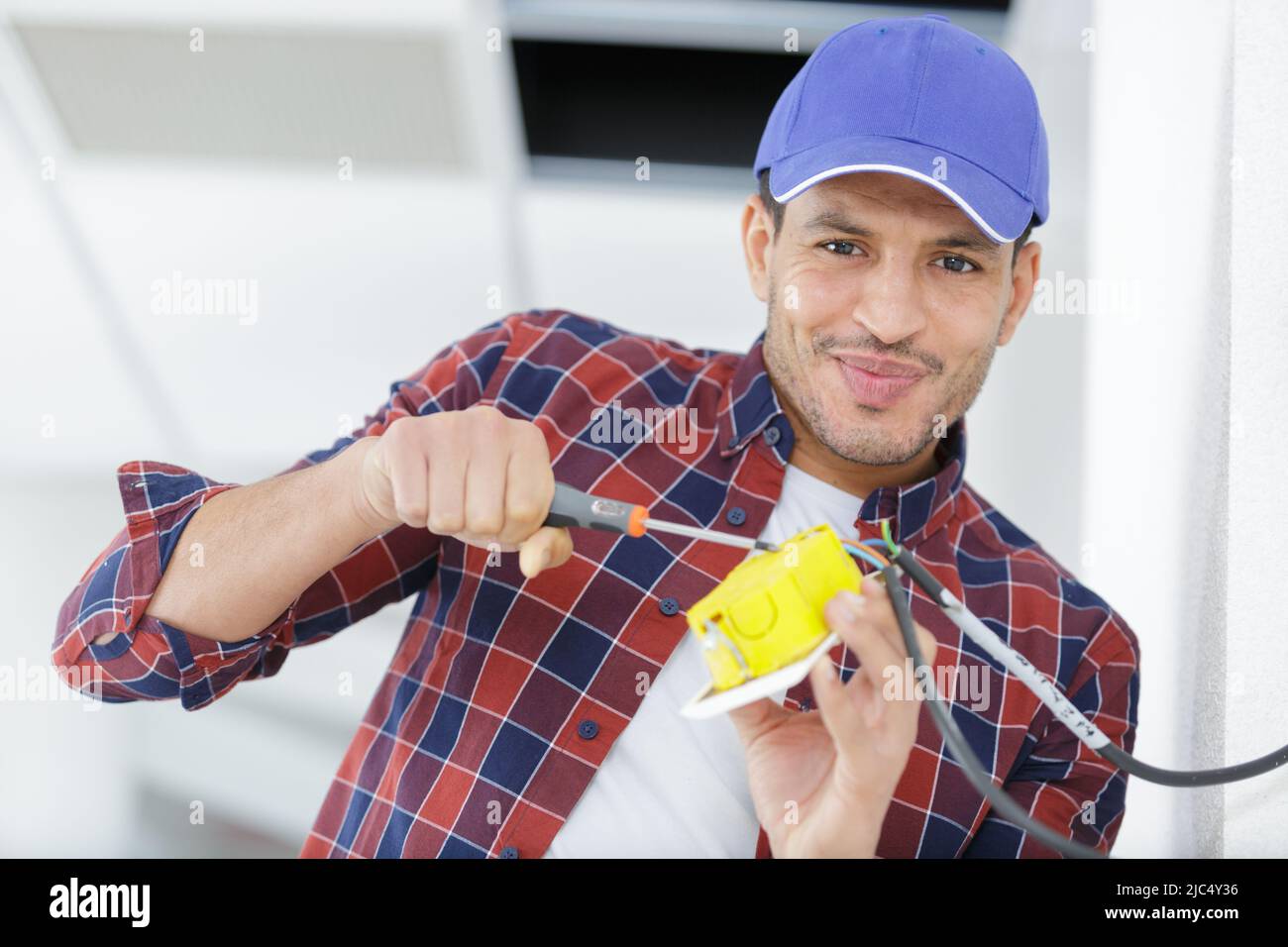 electrician with exposed wiring installing switch Stock Photo