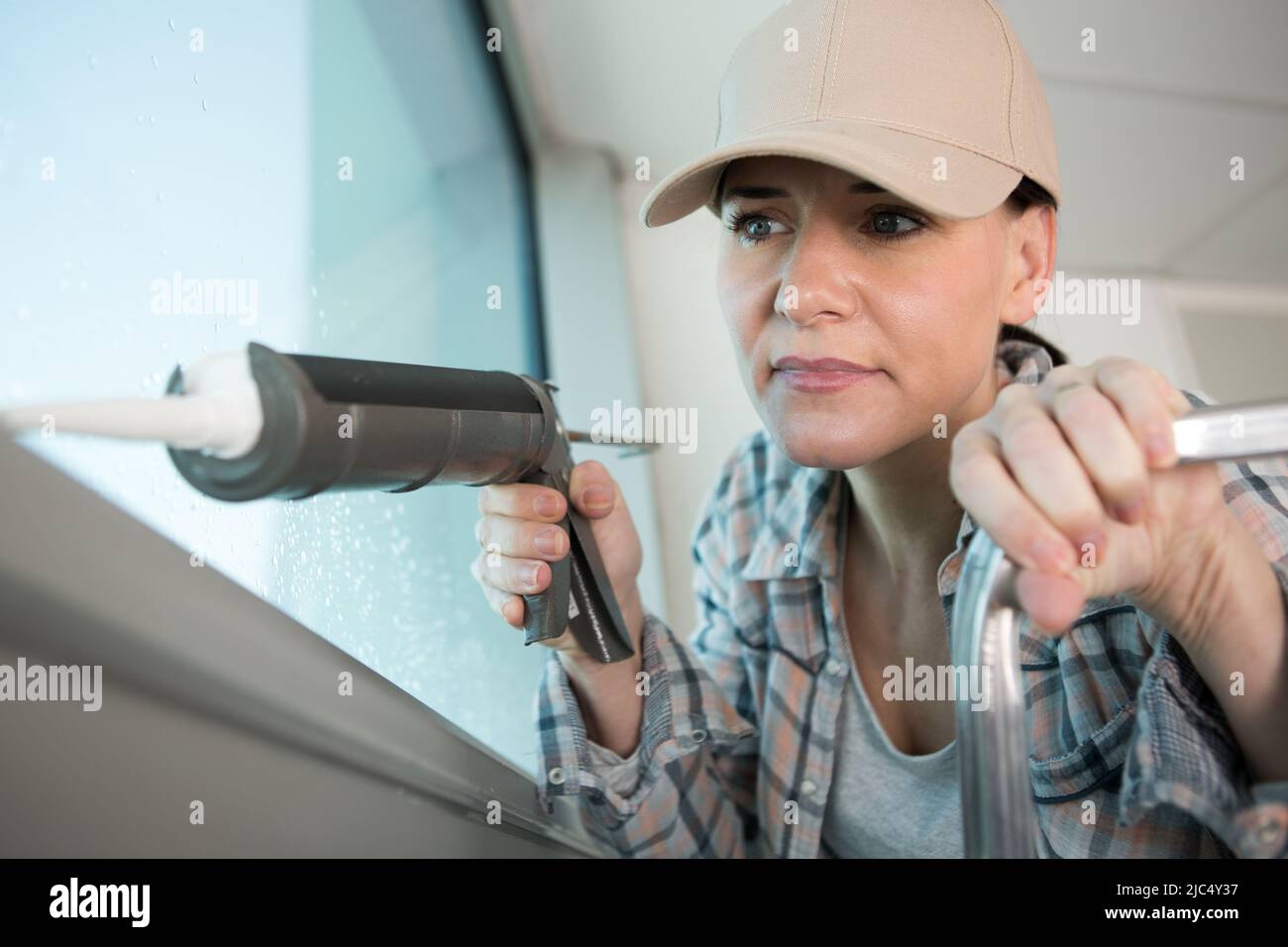 woman window installer applying caulking Stock Photo