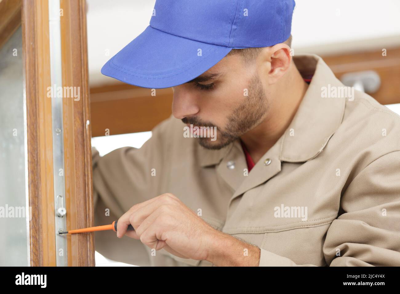 a man fixes basis blinds to frame the window Stock Photo