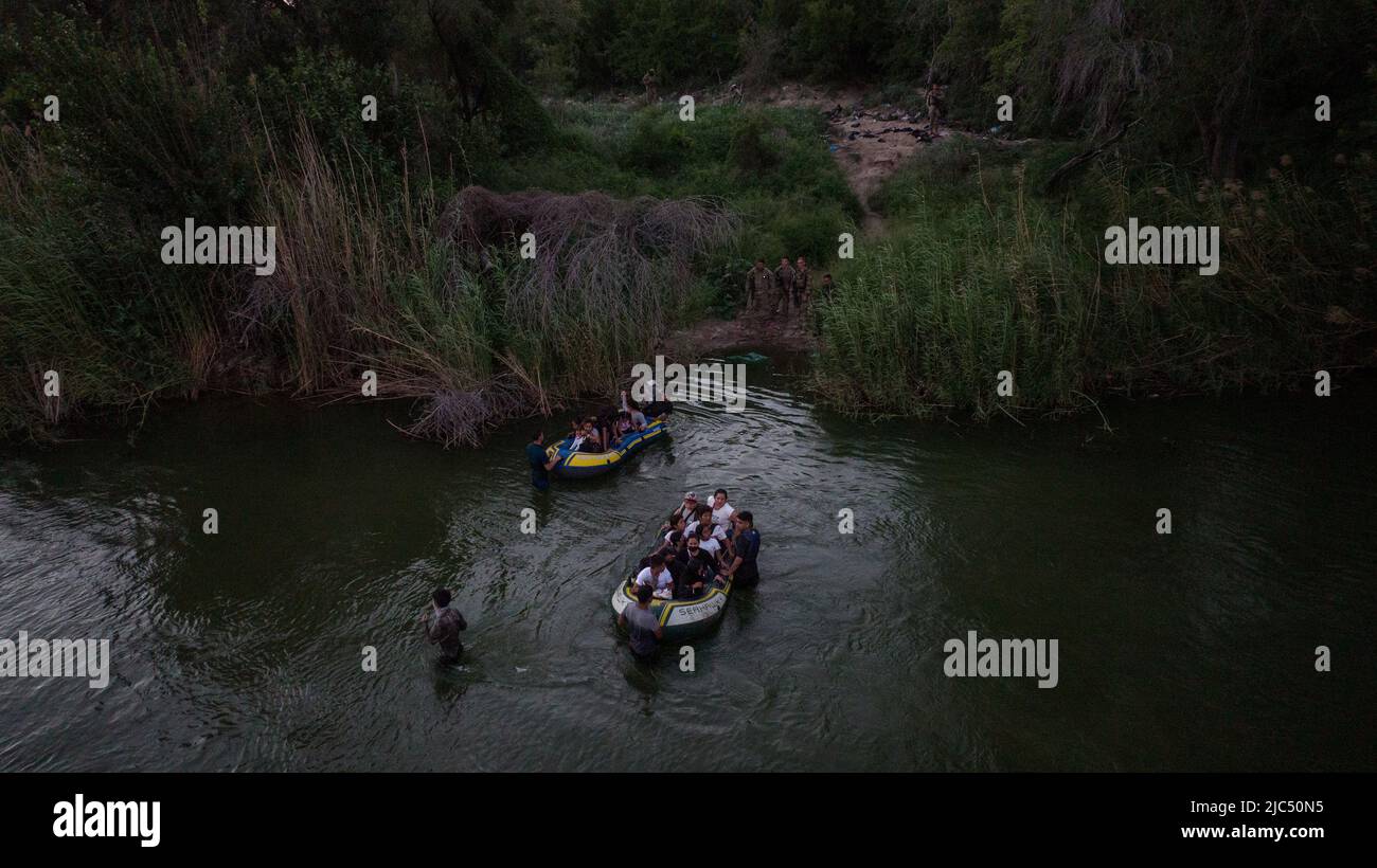 Texas Army National Guard and a border patrol agent stand along the bank as asylum seeking migrants from Central and South America approach on rafts after crossing the Rio Grande River, in Roma, Texas, U.S., June 9, 2022. Picture taken June 9, 2022. Picture taken with a drone.  REUTERS/Adrees Latif     TPX IMAGES OF THE DAY Stock Photo