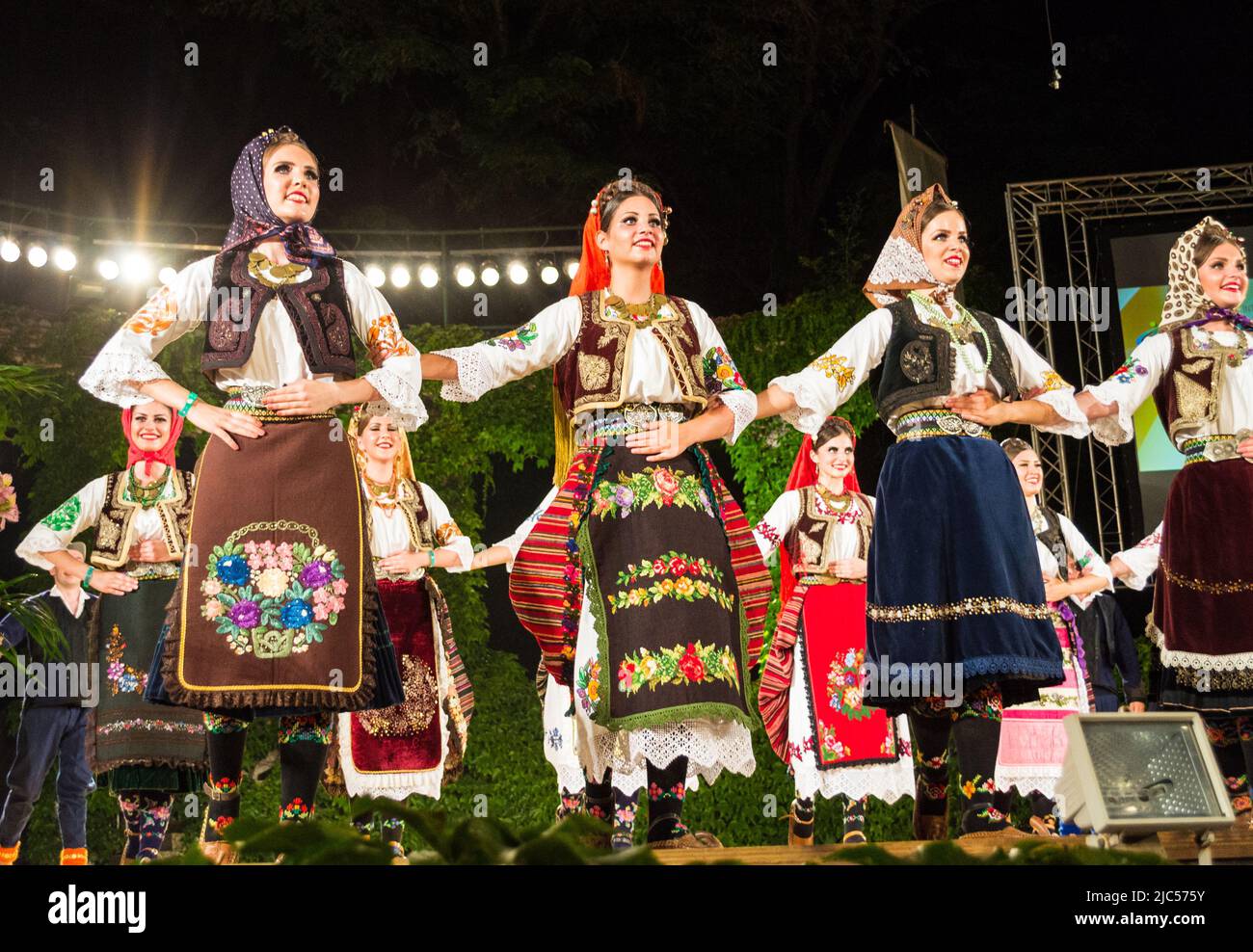Serbian dancers dressed in traditional costumes performing at the stage