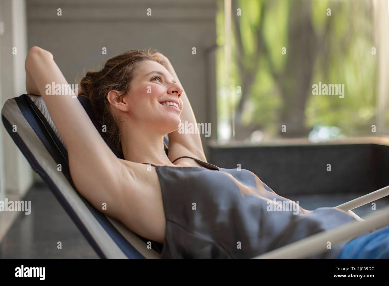 Side profile of a young woman sitting on chair and dreaming Stock Photo