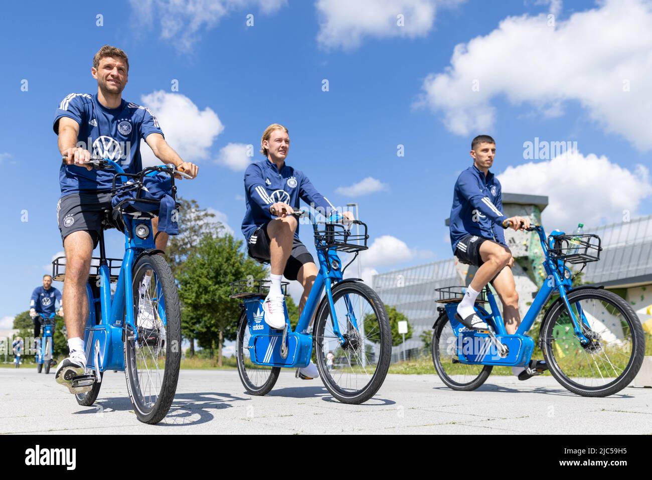 Herzogenaurach, Germany. 10th June, 2022. Soccer: National team, before the Nations League match in Hungary. Players Thomas Müller (l-r), Julian Brandt and Kai Havertz arrive at training on their bikes. Credit: Daniel Karmann/dpa - IMPORTANT NOTE: In accordance with the requirements of the DFL Deutsche Fußball Liga and the DFB Deutscher Fußball-Bund, it is prohibited to use or have used photographs taken in the stadium and/or of the match in the form of sequence pictures and/or video-like photo series./dpa/Alamy Live News Stock Photo