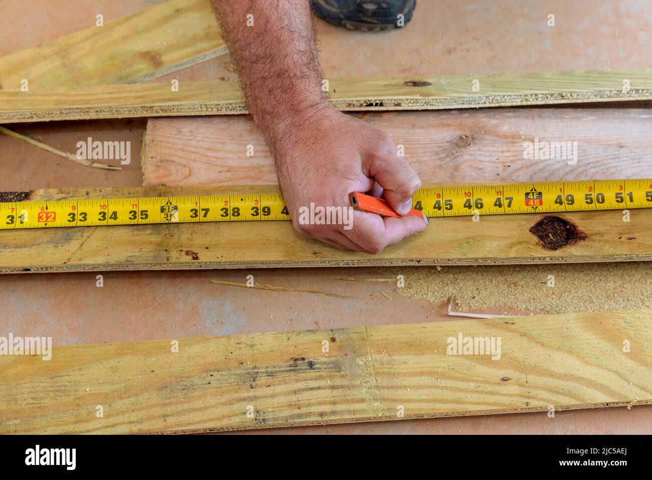 The hand with a pencil with measuring length of board to cut Stock
