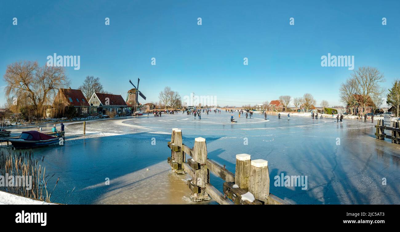 Scating on a frozen canal near a windmill called De Paauw *** Local Caption ***  Netherlands,windmill, water, winter, snow, ice, people, scaters,  ,Na Stock Photo