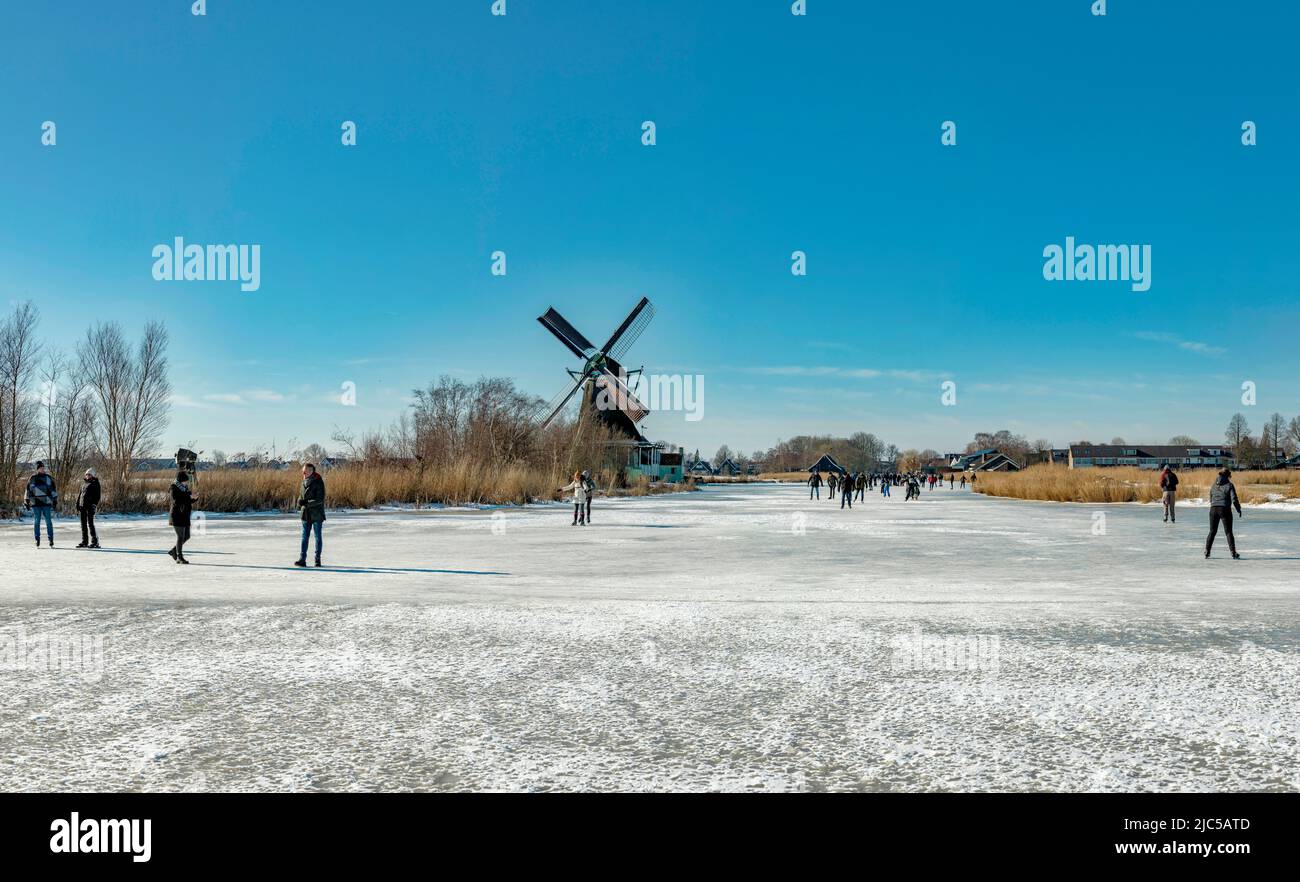 Scating on a frozen canal near a windmill called Het Prinsenhof *** Local Caption ***  Netherlands,windmill, field,  meadow, water, winter, snow, ice, Stock Photo