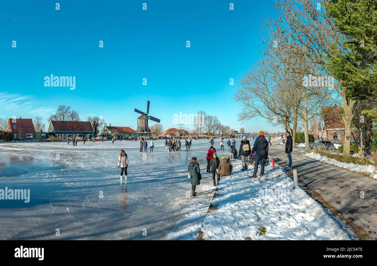 Scating on a frozen canal near a windmill called De Paauw *** Local Caption ***  Netherlands,windmill, water, winter, snow, ice, people, scaters,  ,Na Stock Photo