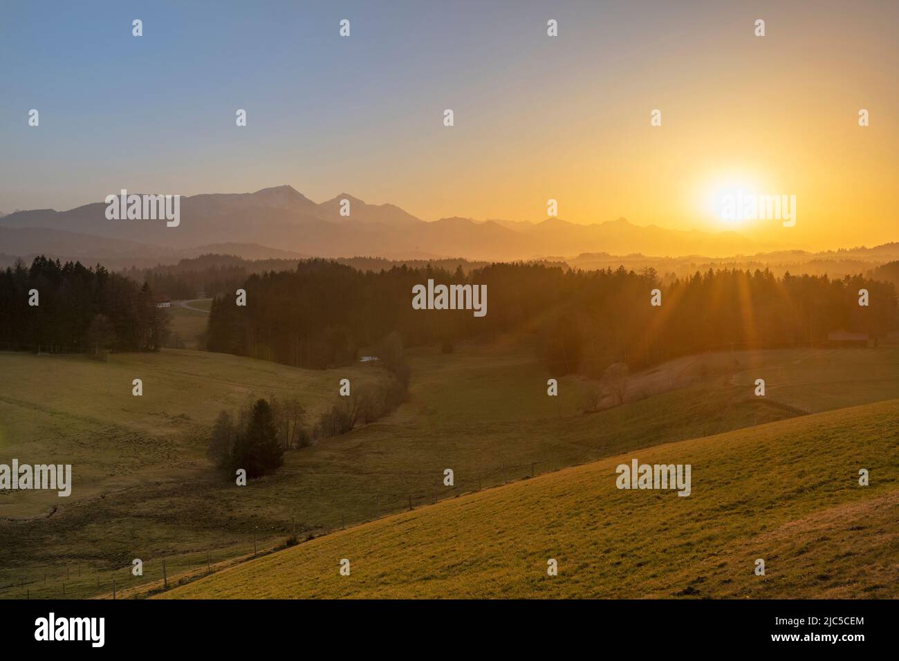 Sonnenuntergang hinter den Chiemgauer Bergen  (Surbergbichl - Neukirchen - Surberg)  Stimmung mit Saharastaub Stock Photo