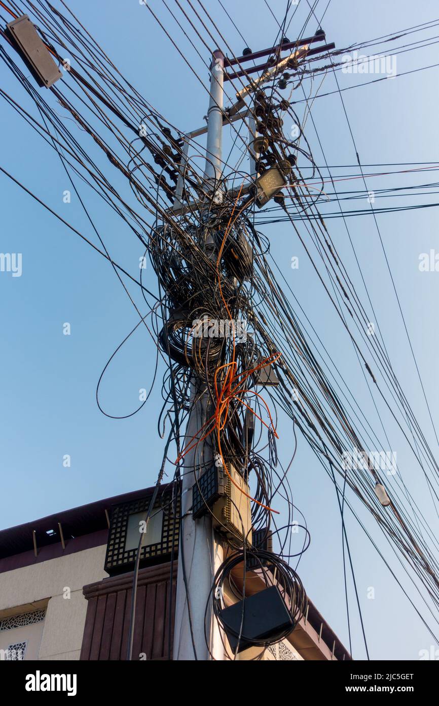 Electricity poles with overcrowded wires and distribution box in India. Stock Photo