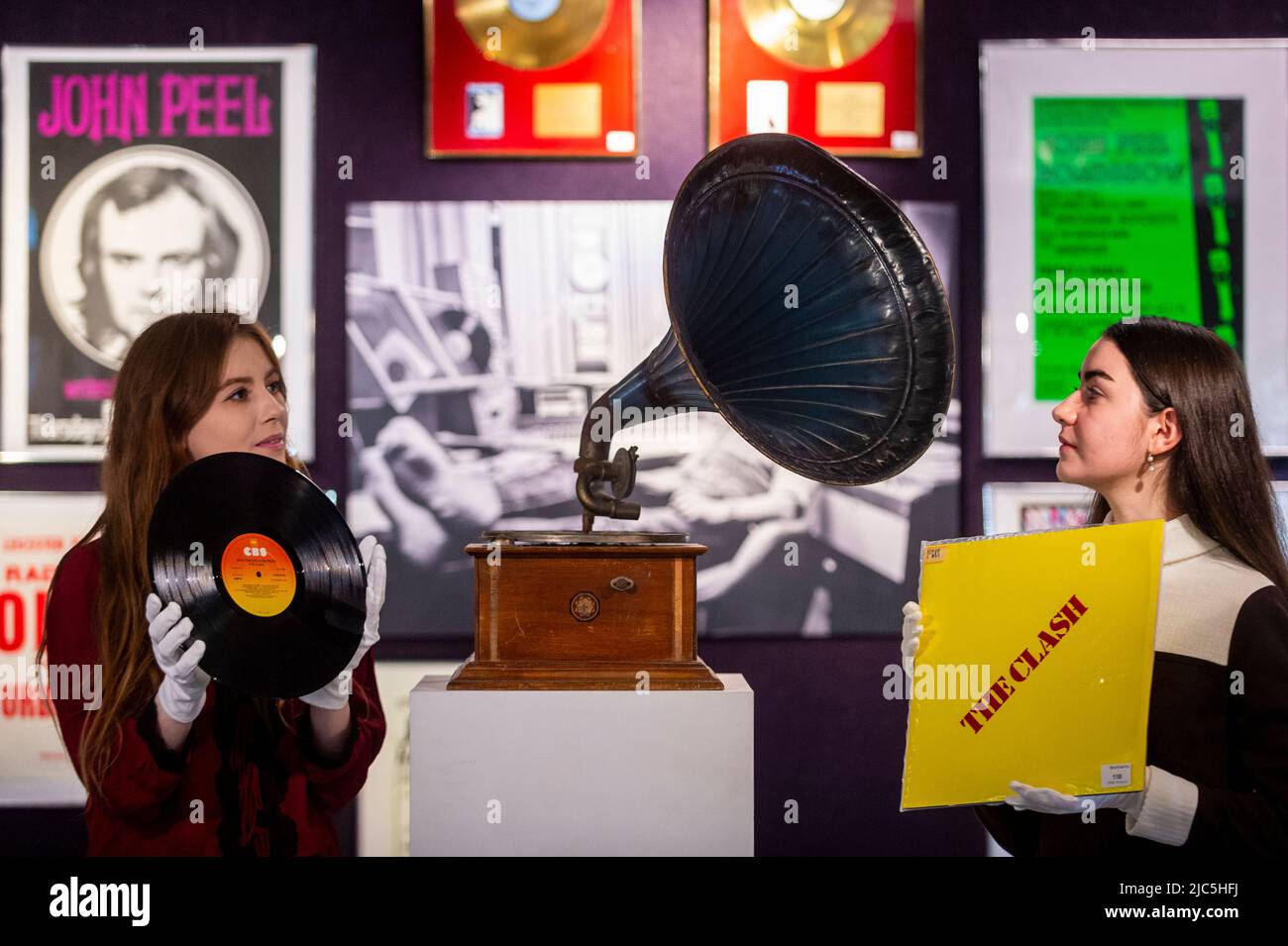 London, UK.  10 June 2022. Staff members with 'Give 'Em Enough Rope' by The Clash, 1978, (Est. £1,000-1,500) and a 'A vintage horn gramophone', first half 20th century, (Est. £500-700) at the preview of “Live In Session: Property from the John Peel Archive” at Bonhams Knightsbridge.  Items from the music collection of the late John Peel, the BBC Radio DJ, journalist and broadcaster, will be offered for sale on 14 June.  Credit: Stephen Chung / Alamy Live News Stock Photo