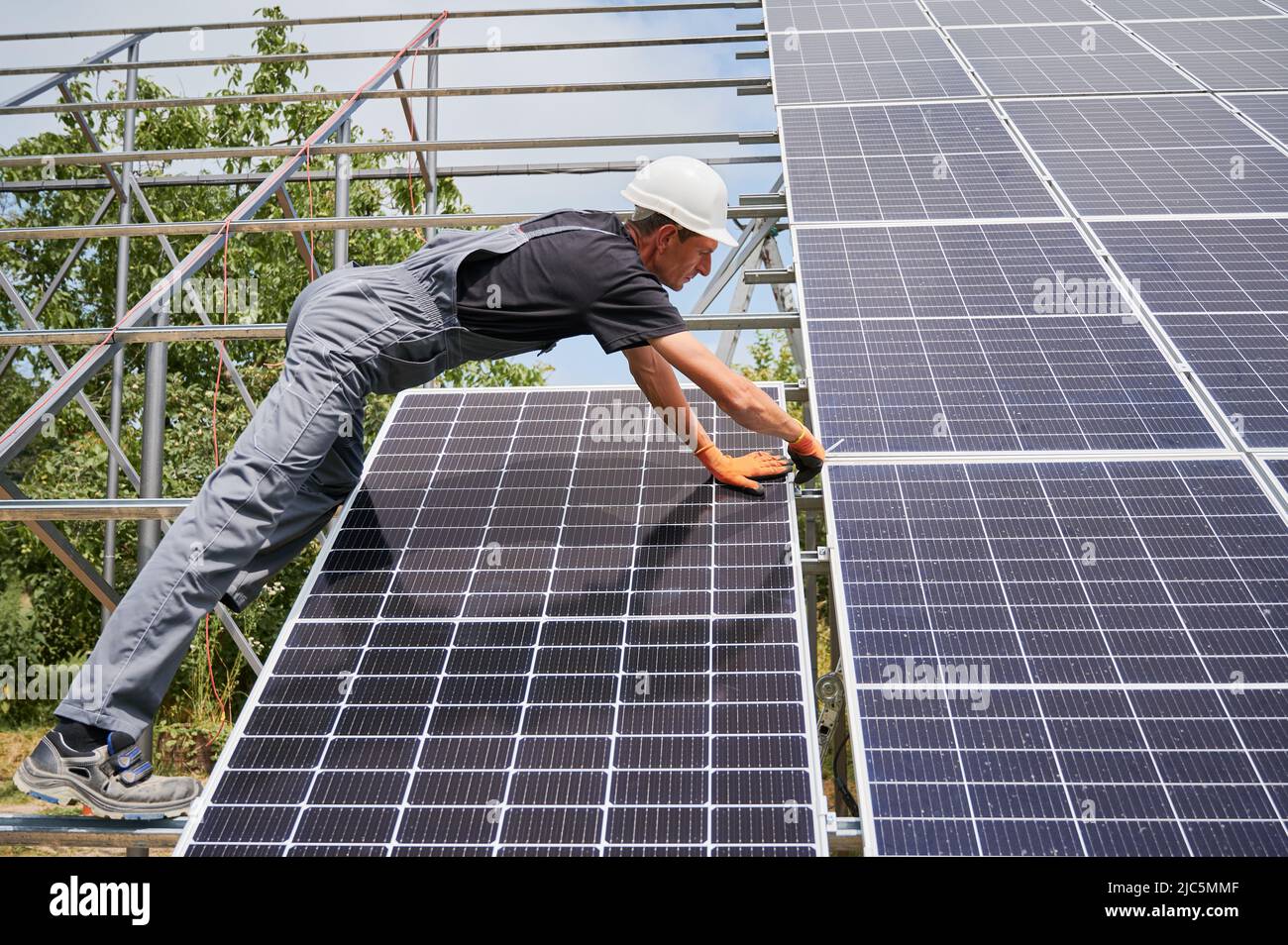 Man engineer solar installer placing solar module on metal rails. Male worker installing photovoltaic solar panel system. Concept of alternative energy and power sustainable resources. Stock Photo
