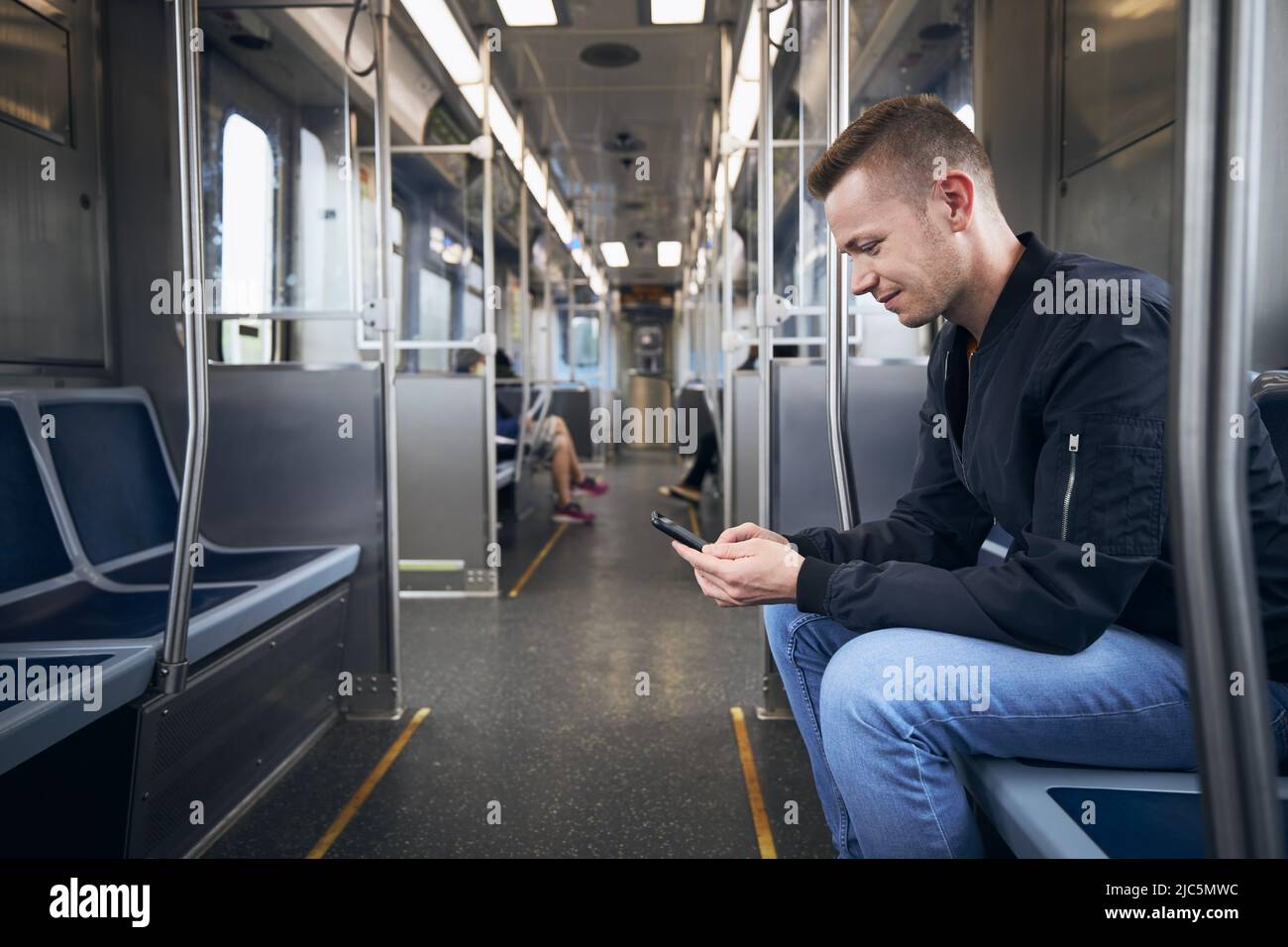 Side view of passenger while using phone. Man commuting by train of public transportation. Stock Photo