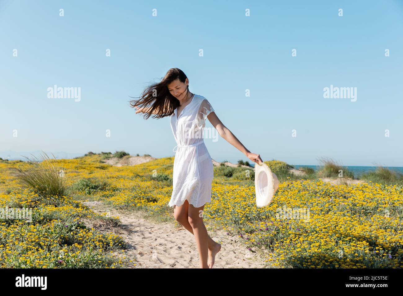 Positive young woman holding sun hat and having fun on beach Stock ...