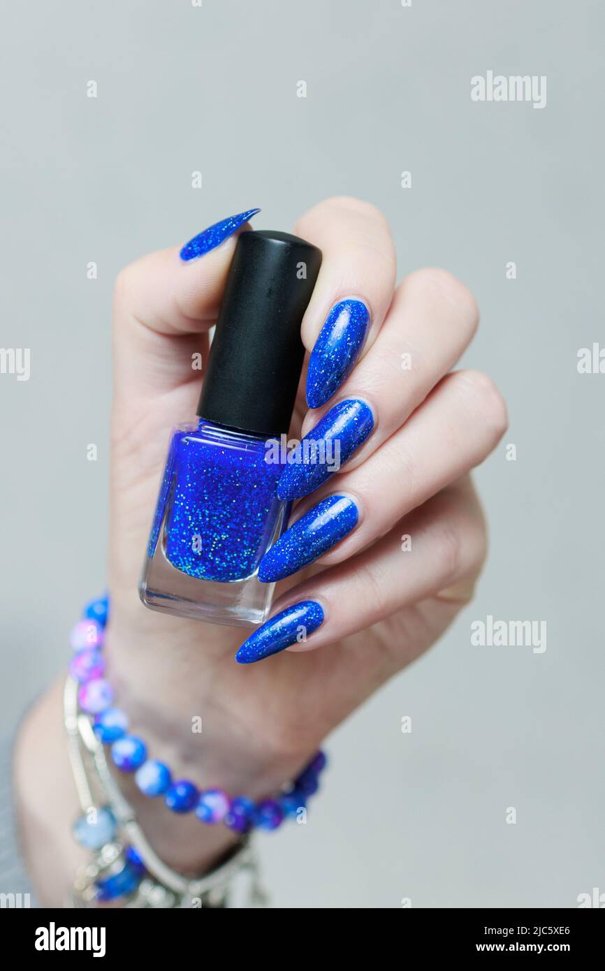 Female hand with long nails and a bottle of light blue color nail polish  Stock Photo - Alamy