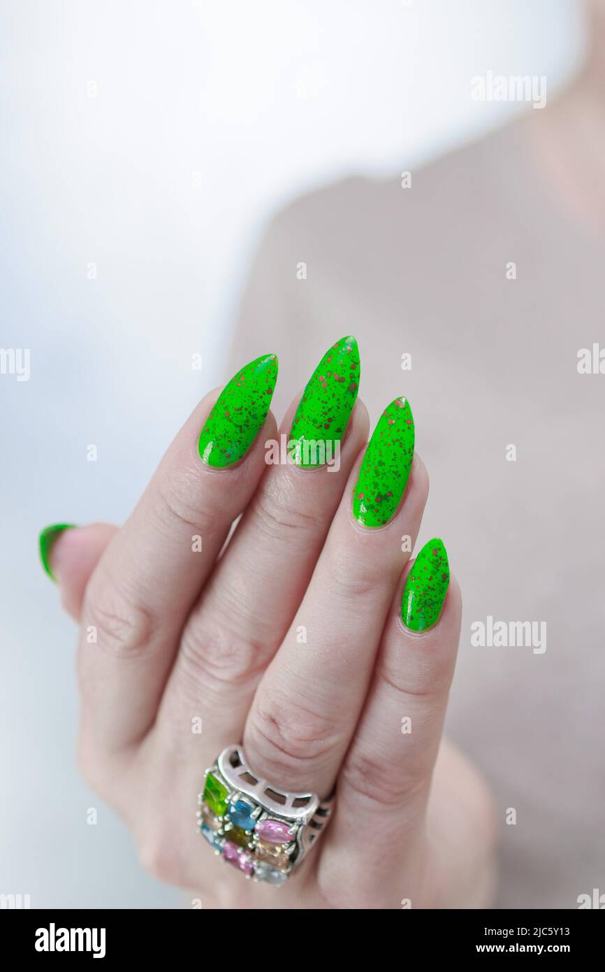 Female hand with long nails and neon green manicure with bottles of nail  polish Stock Photo - Alamy