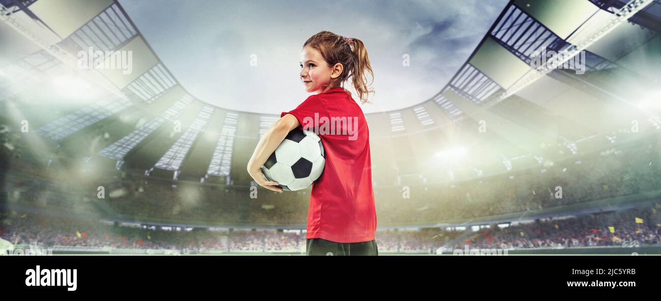 Portrait of little girl, football player in red uniform standing with