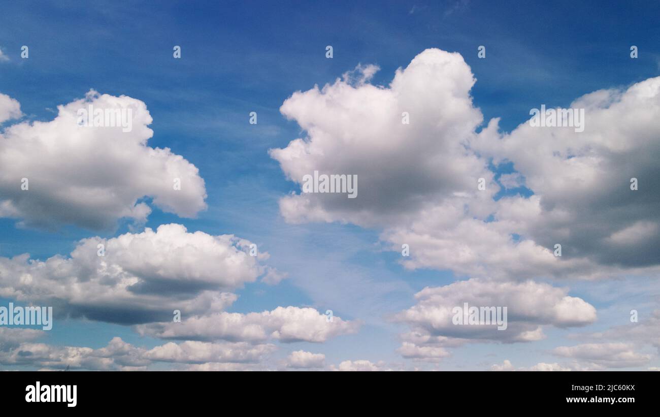 Fluffy clouds on the blue sky. Drone panning. Stock Photo