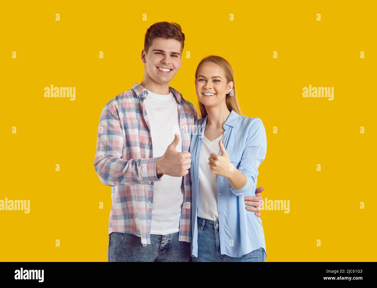 Portrait of happy satisfied young man and woman smiling and giving thumbs up together Stock Photo