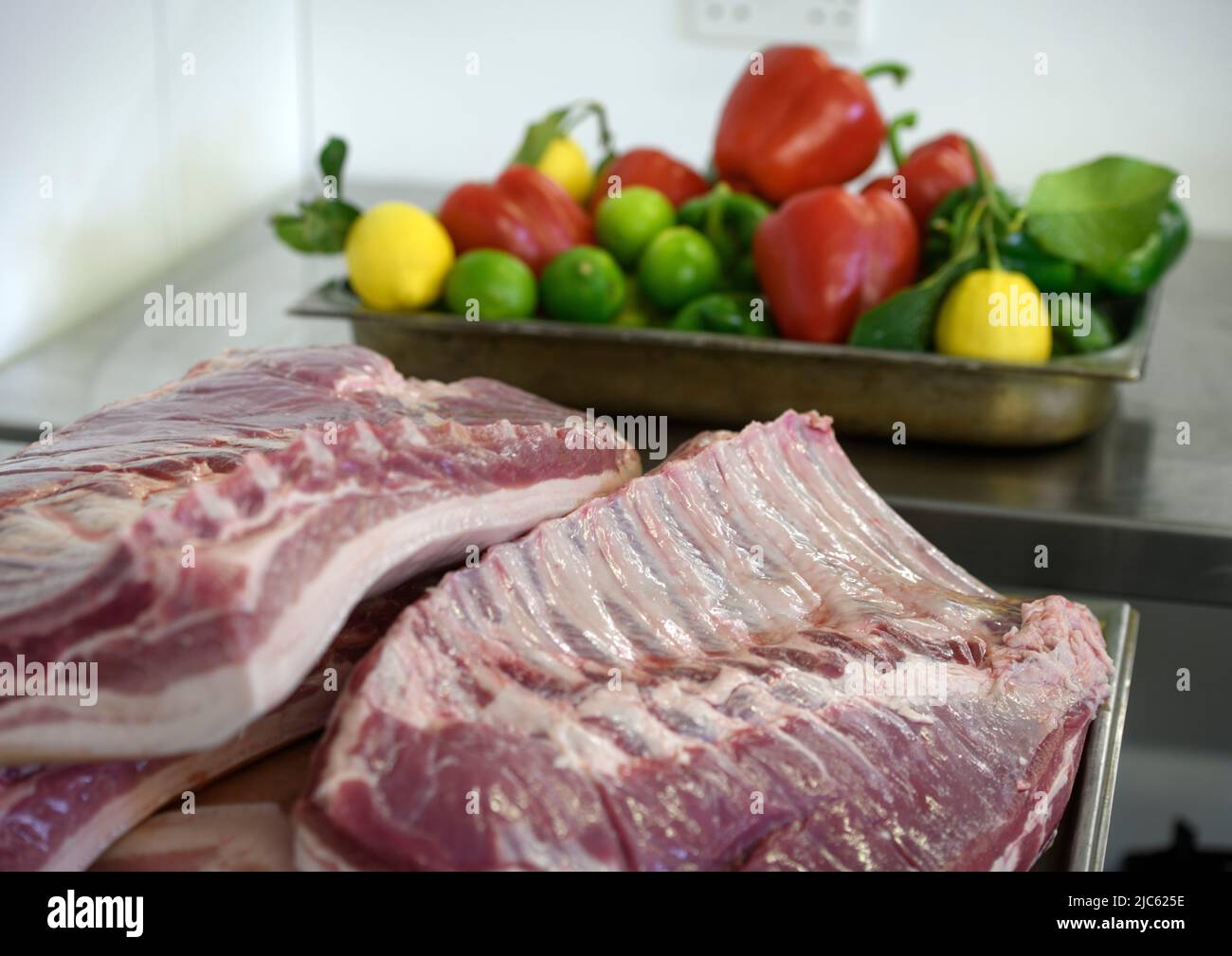 Pork ribs and a tray of colourful fuit and vegetables. Stock Photo
