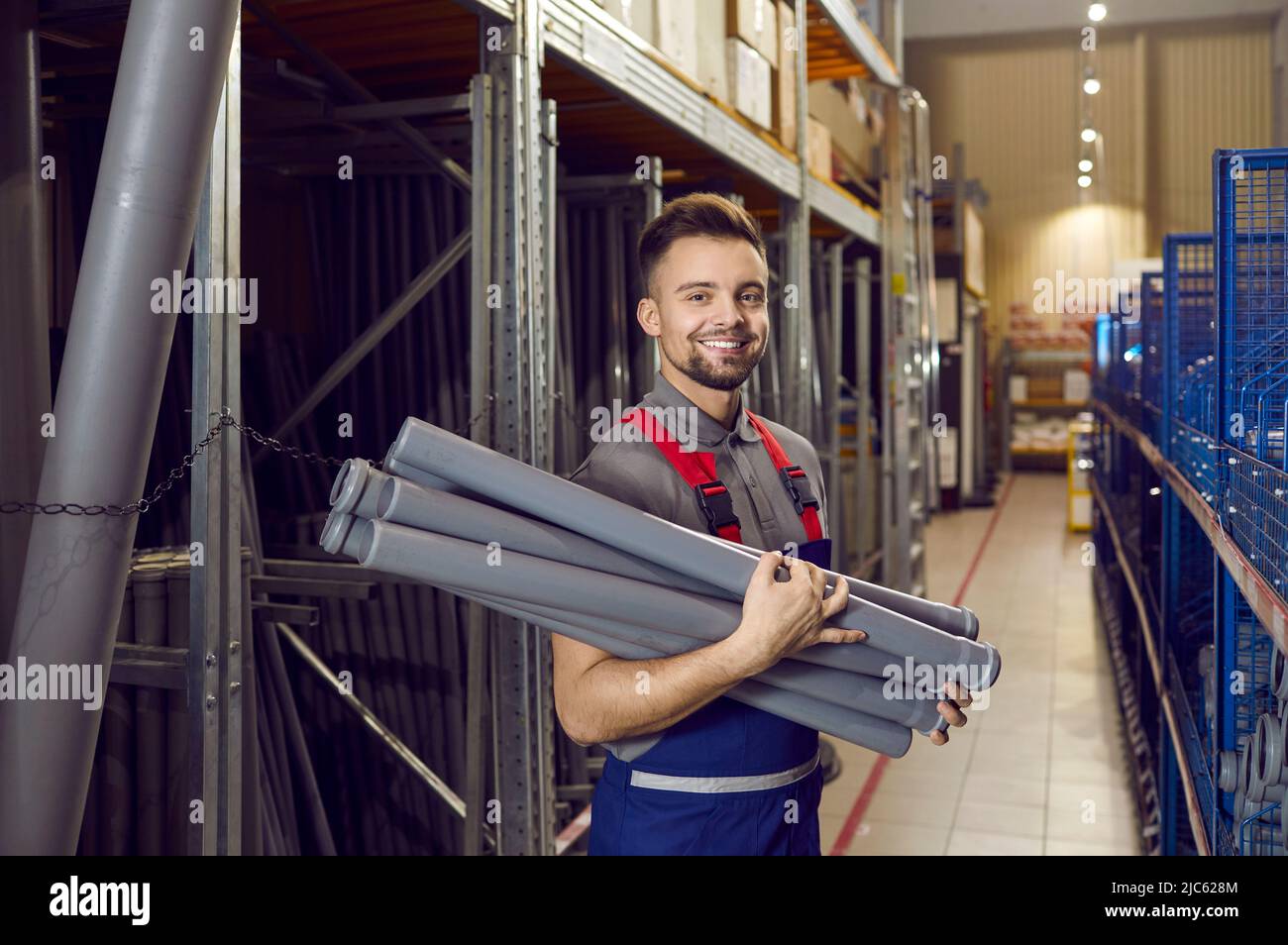 Warehouse worker at building materials store stands with plumbing pipes
