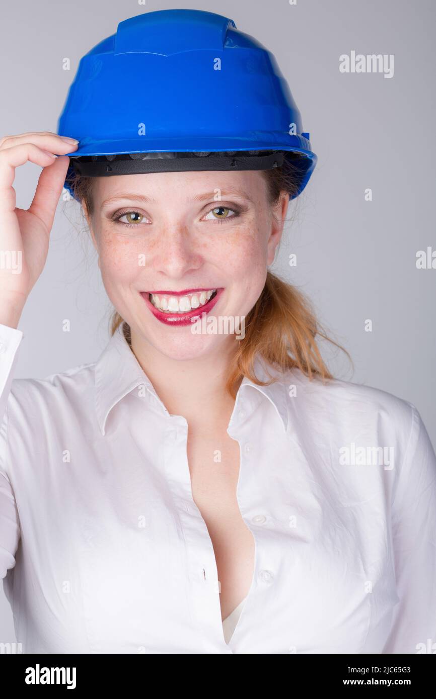 Young female engineer wearing a blue hard hat shows a big smile Stock Photo Alamy