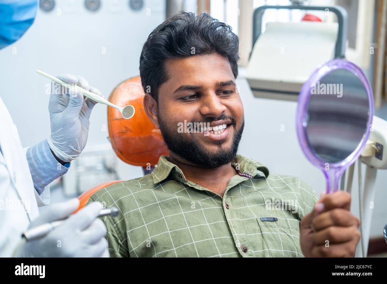 Happy smiling patient watching mirror after teeth treatment or oral