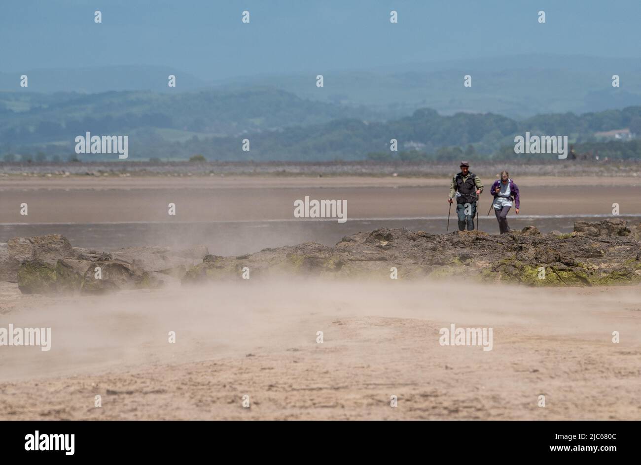 Arnside, Milnthorpe, Cumbria, UK Friday 10th June 2022 Walkers coping with the wind blown sand on a windy afternoon at Arnside, Cumbria. Credit: John Eveson/Alamy Live News Stock Photo