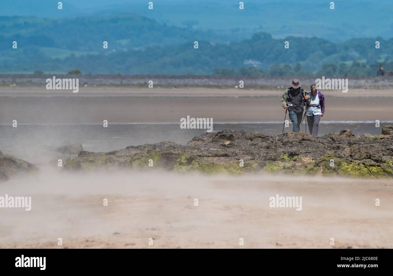 Arnside, Milnthorpe, Cumbria, UK Friday 10th June 2022 Walkers coping with the wind blown sand on a windy afternoon at Arnside, Cumbria. Credit: John Eveson/Alamy Live News Stock Photo