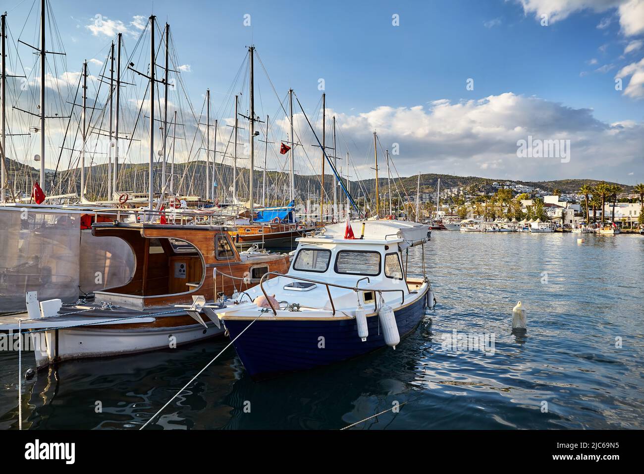 View of Bodrum Beach from Promenade. Sailing boats, yachts at Aegean sea with traditional white houses at hills in Bodrum port town Turkey Stock Photo