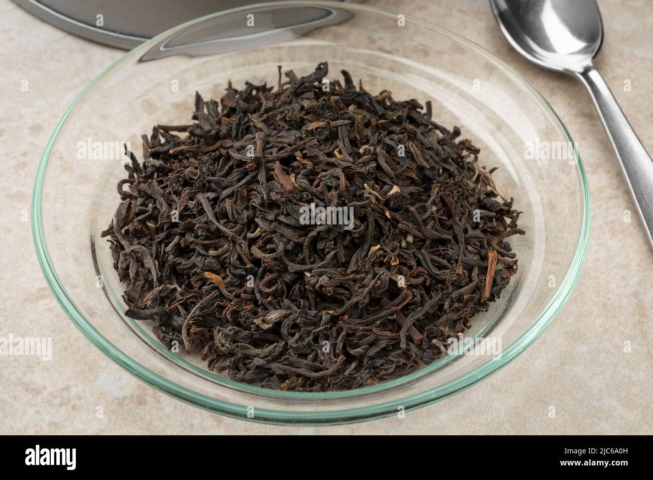 Glass bowl with dried aromatic Indian Assam tea leaves close up Stock Photo