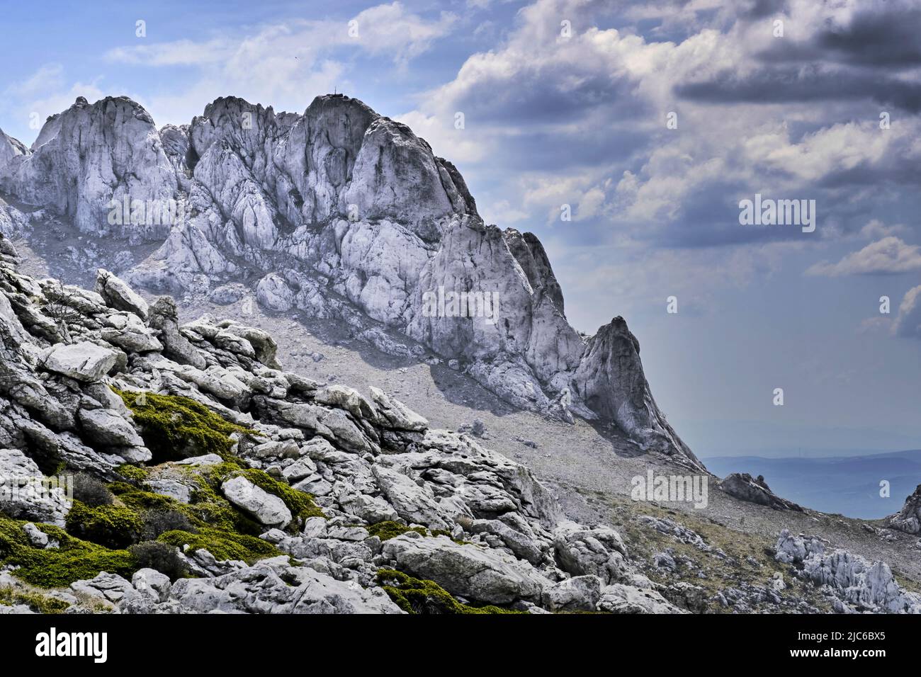 A rugged ridge of light limestone against a cloudy sky in the Velebit Mountains, Croatia Stock Photo