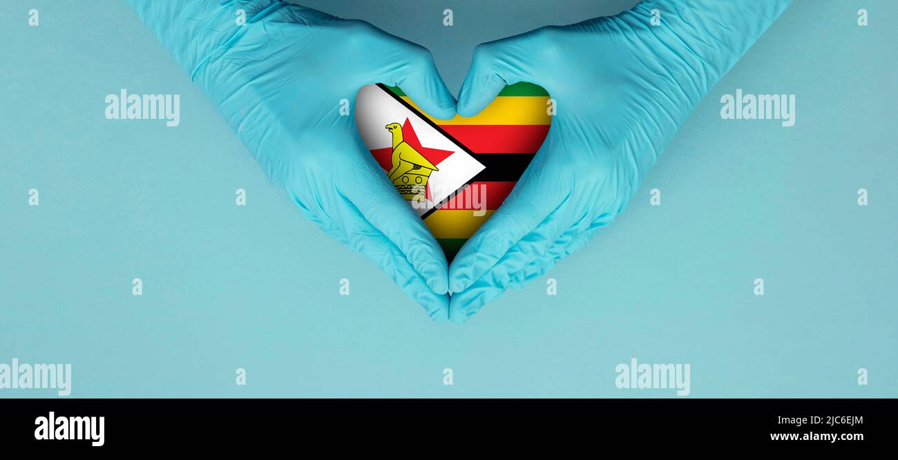 Doctors hands wearing blue surgical gloves making hear shape symbol with zimbabwe flag Stock Photo