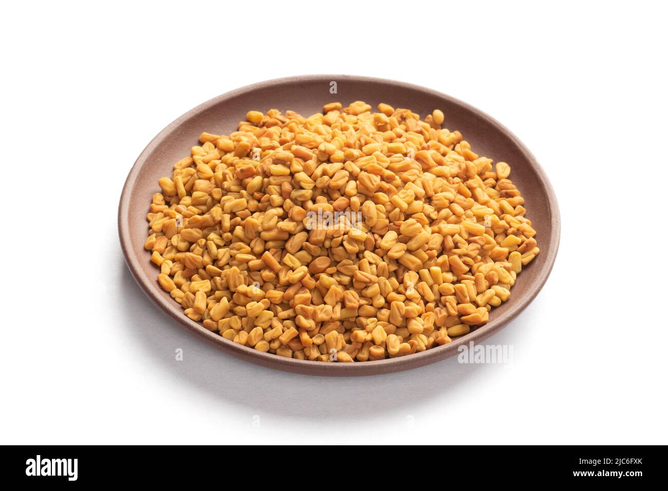 Fenugreek (Trigonella foenumgraecum) in clay plate on white background