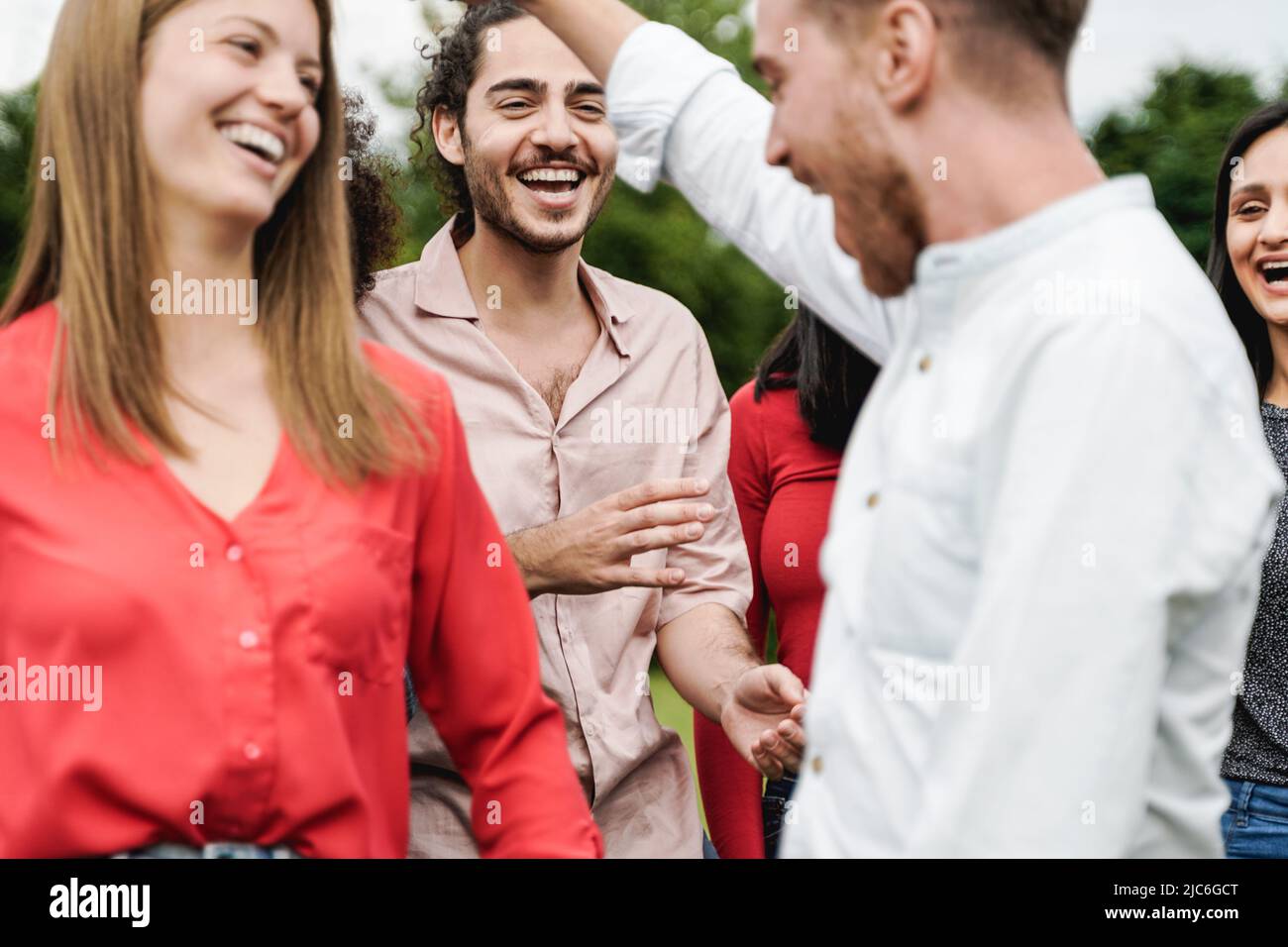 Multiethnic group of friends having fun dancing together outdoor during summer vacations - Focus on center man face Stock Photo