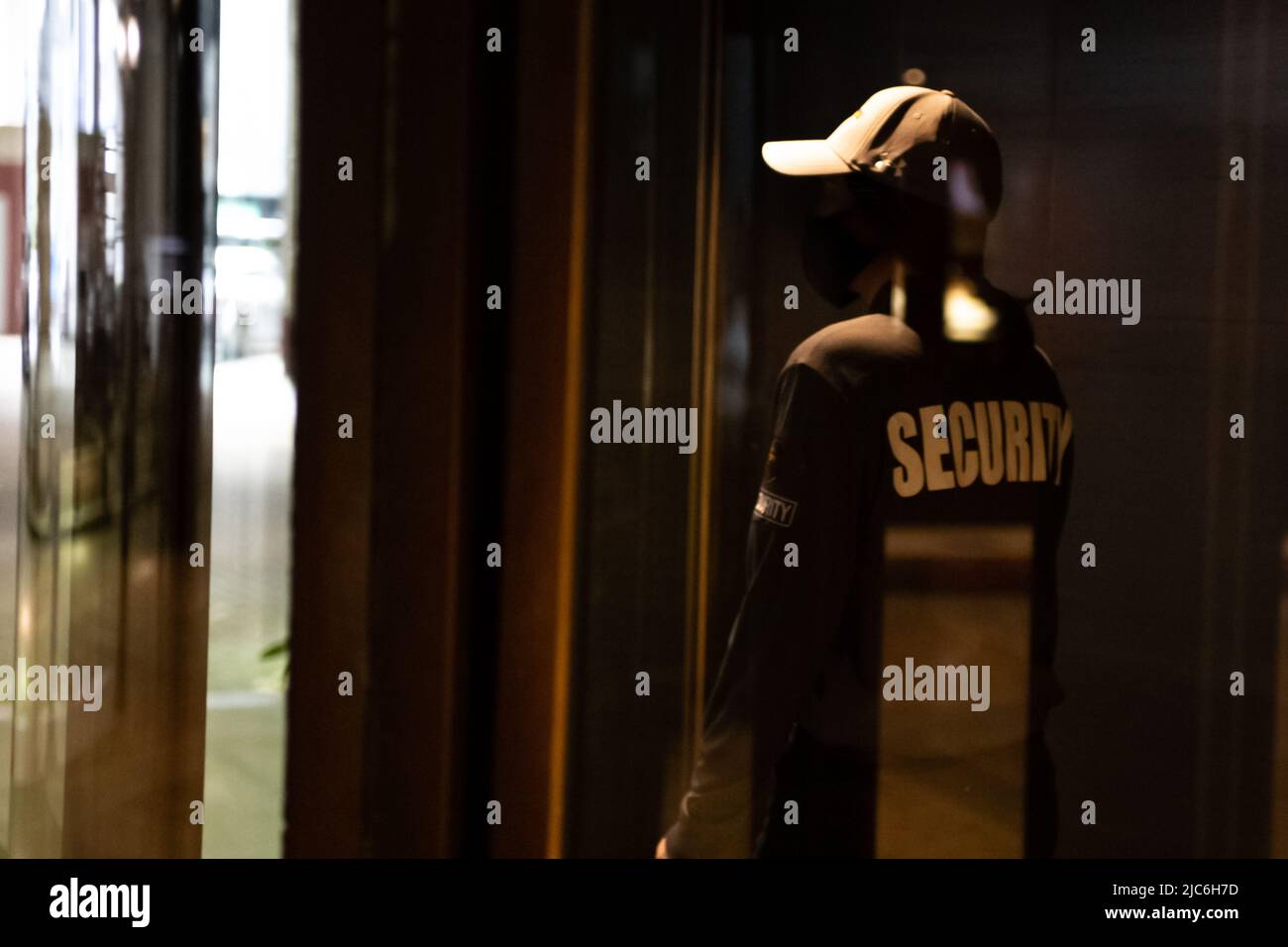 Female security guard walking through an automated revolving curved sliding door to patrol a commercial area Stock Photo