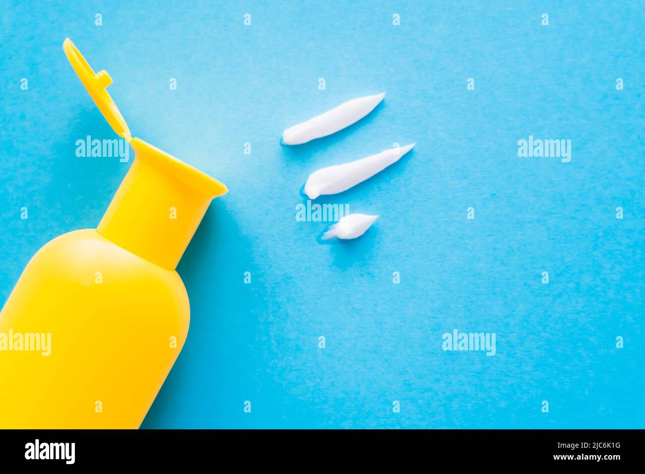 Top view of sunscreen near cream strokes on blue background Stock Photo