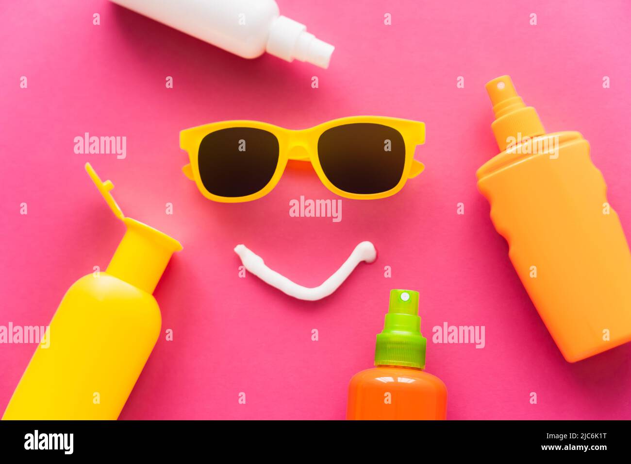 Top view of sunglasses near bottles of sunscreens on pink background Stock Photo