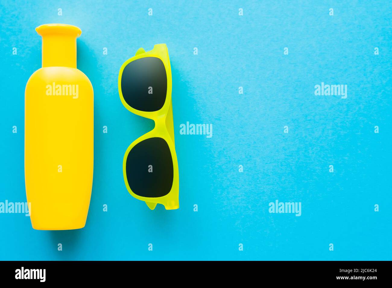 Top view of sunglasses and sunscreen on blue background with copy space Stock Photo