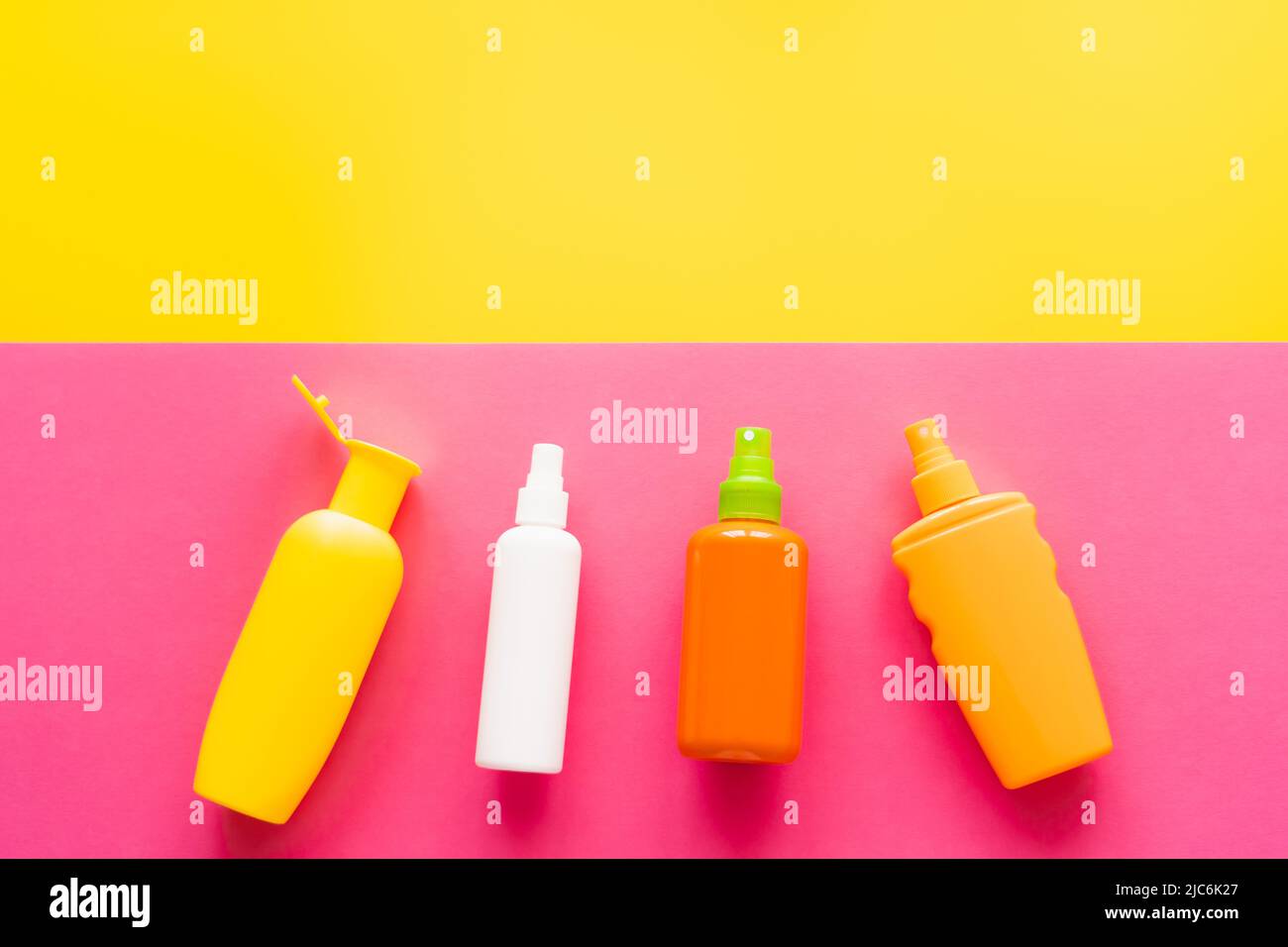 Top view of bottles of sunscreens on yellow and pink background Stock Photo