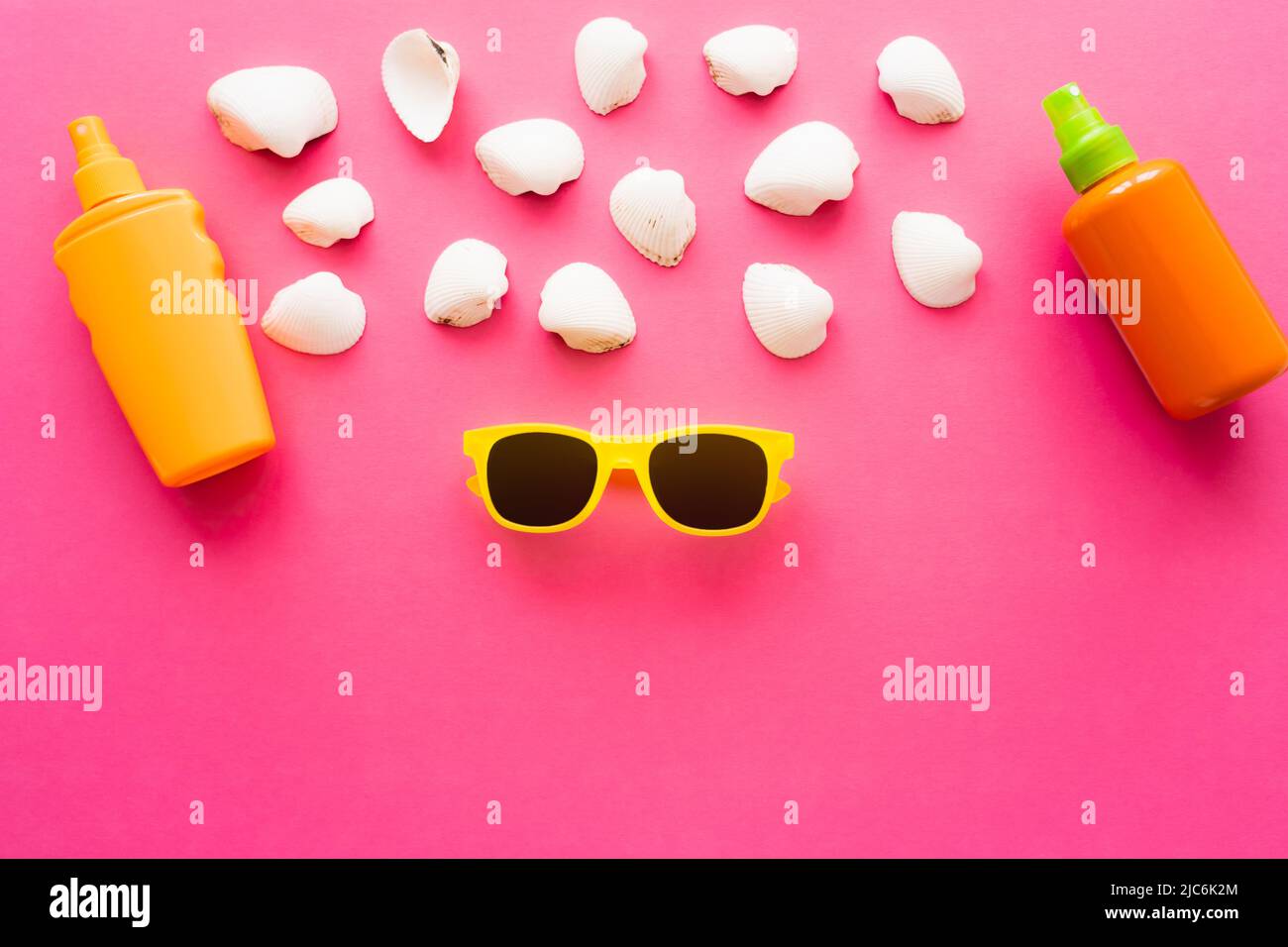 Top view of sunglasses near seashells and sunscreens on pink background Stock Photo