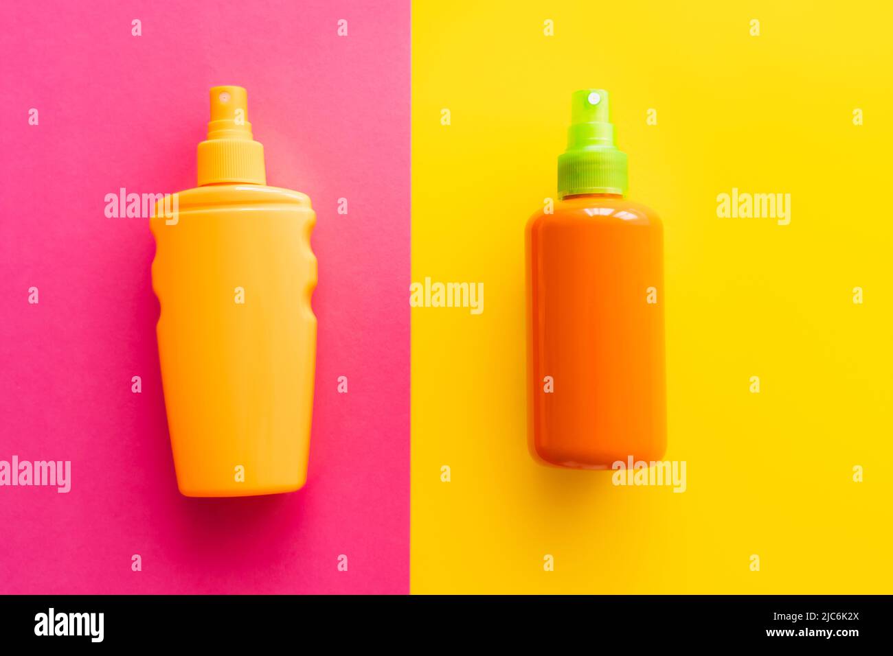 Top view of bottles of sunscreens on pink and yellow background Stock Photo