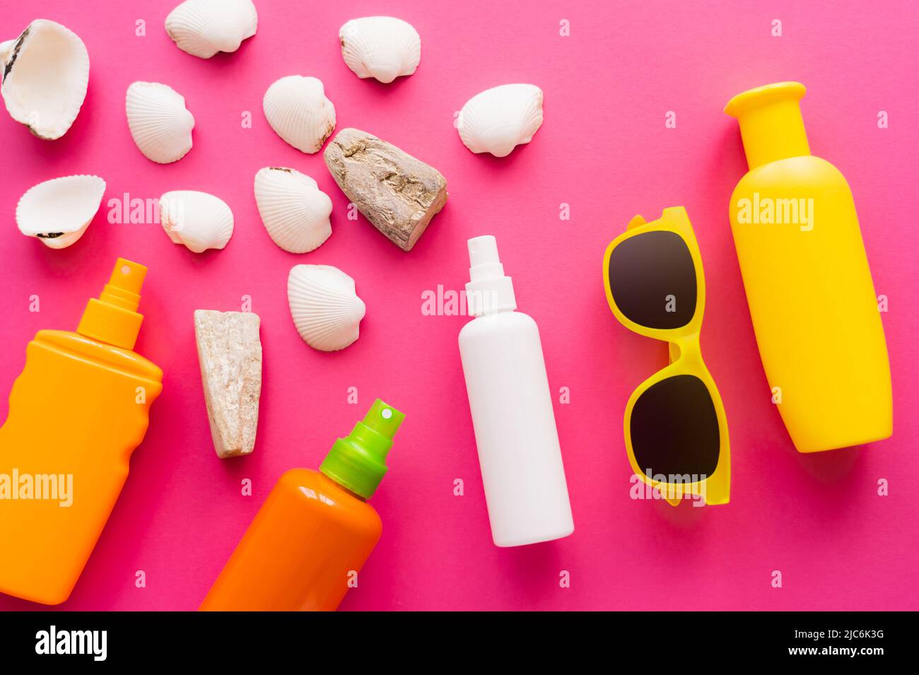 Top view of sunglasses and sunscreens near white seashells on pink background Stock Photo