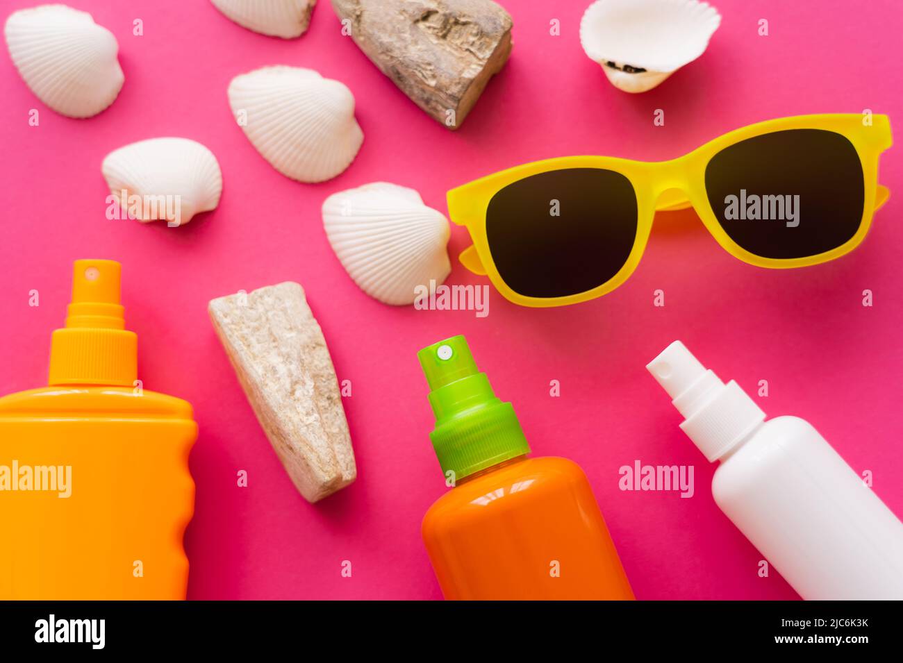 Top view of sunscreens near sunglasses and seashells on pink background Stock Photo