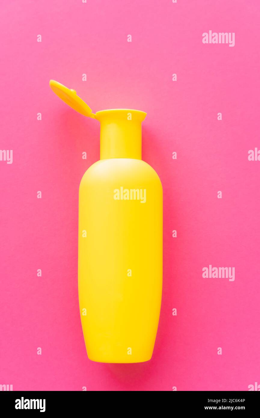 Top view of yellow bottle of sunscreen on pink surface Stock Photo